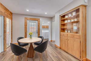 Dining room with LVP flooring, built in cabinets, backyard access, and recessed lighting
