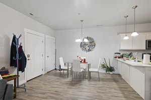 Kitchen featuring stainless steel microwave, light countertops, a chandelier, and light wood-style floors