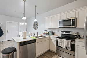 Kitchen featuring stainless steel appliances, a sink, a peninsula, and light countertops