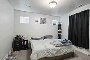 Carpeted bedroom with a textured ceiling and baseboards