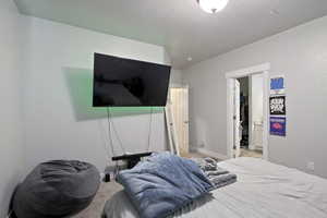 Bedroom featuring baseboards, light colored carpet, a spacious closet, a textured ceiling, and a closet