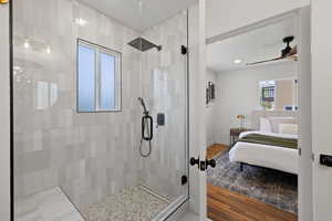 Ensuite bathroom featuring a tile shower, wood finished floors, a ceiling fan, baseboards, and recessed lighting