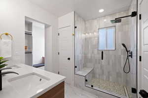 Full bathroom with a stall shower, double vanity, marble finish floors, and recessed lighting