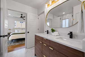 Ensuite bathroom with plenty of natural light, marble look tiles, ceiling fan, double vanity, and recessed lighting