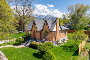 Tudor-style house with a chimney, brick siding, a mountain view, a shingled roof, and cooling unit