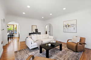 Living room featuring arched walkways, wood finished floors, recessed lighting, and baseboards