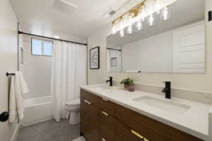 Full bathroom with toilet, shower / tub combo with curtain, and double vanity