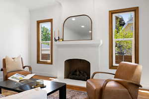 Living area with a fireplace with raised hearth, wood finished floors, and baseboards