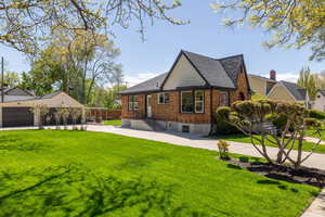 View of side of property featuring brick siding, a lawn, and roof with shingles