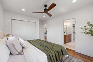 Bedroom with a closet, wood finished floors, recessed lighting, baseboards, and ensuite bathroom