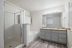 Bathroom with a stall shower, wood finished floors, a garden tub, and double vanity