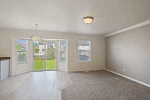 Spare room with crown molding, wood finished floors, a textured ceiling, and baseboards