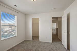 Unfurnished bedroom with carpet flooring, a walk in closet, baseboards, and a closet