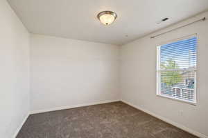 Unfurnished room featuring dark colored carpet and baseboards