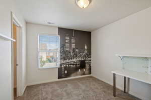 Carpeted empty room featuring a textured ceiling and baseboards