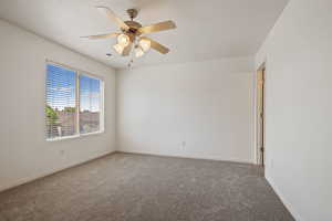 Carpeted empty room with baseboards and ceiling fan