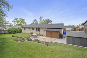 Rear view of property with a patio area, a storage unit, brick siding, an outbuilding, and roof with shingles