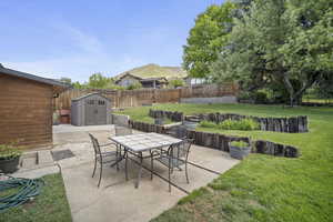 View of patio with a storage shed, outdoor dining area, and an outbuilding