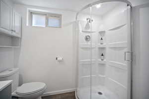 Full bath with wood finished floors, a stall shower, vanity, toilet, and baseboards