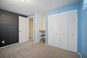Unfurnished bedroom featuring carpet floors, a closet, baseboards, and a textured ceiling