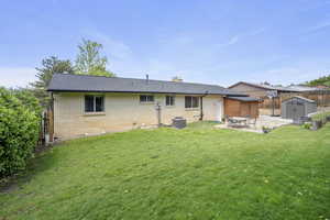 Back of house featuring a storage unit, a patio, brick siding, an outbuilding, and a chimney