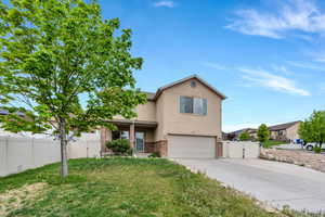 Traditional home with an attached garage, a gate, stucco siding, concrete driveway, and a front yard