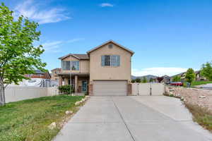 Traditional-style home featuring an attached garage, a gate, stucco siding, fence, and driveway