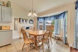 Dining room featuring light tile patterned floors, a chandelier, and baseboards