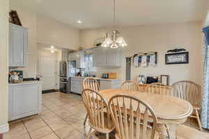 Dining area featuring light tile patterned floors, a chandelier, vaulted ceiling, and recessed lighting