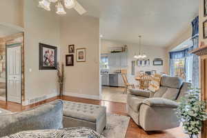 Living area featuring lofted ceiling, healthy amount of natural light, ceiling fan, a chandelier, and light wood-style floors