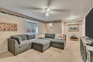 Living area with carpet floors, a ceiling fan, and baseboards