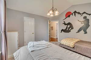 Carpeted bedroom featuring a chandelier, baseboards, and vaulted ceiling
