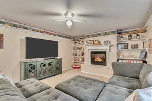 Living room with carpet, ceiling fan, and a glass covered fireplace