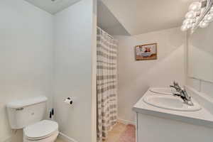 Bathroom featuring toilet, double vanity, a shower with curtain, and tile patterned flooring