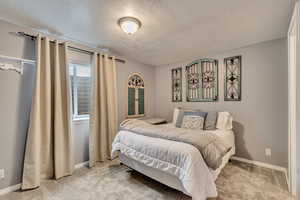 Bedroom featuring light colored carpet, a textured ceiling, and baseboards