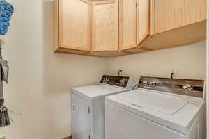 Clothes washing area featuring cabinet space and washer and clothes dryer