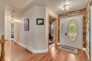Foyer with a textured ceiling, light wood-type flooring, and baseboards