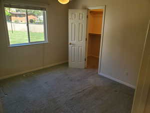 Unfurnished bedroom with a spacious closet, carpet flooring, and baseboards