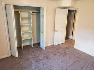 Unfurnished bedroom with carpet floors, baseboards, and a closet
