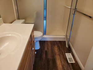 Full bath featuring vanity, a stall shower, and dark wood-style floors