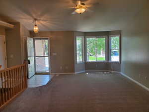 Carpeted entrance foyer with tile patterned floors and a ceiling fan