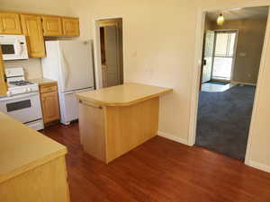 Kitchen with white appliances, light countertops, a peninsula, and dark wood finished floors
