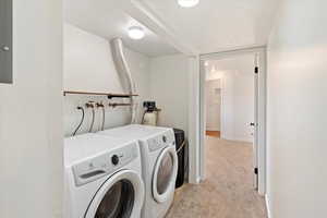 Laundry room with light colored carpet, independent washer and dryer, and baseboards