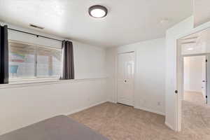 Primary bedroom with carpet floors, a closet, baseboards, and a textured ceiling