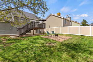 Back of house featuring stairway, a deck, a patio area, an outdoor fire pit, and a chimney