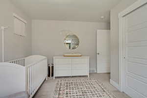 Bedroom with light colored carpet, visible vents, and a crib