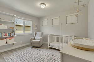 Bedroom featuring light colored carpet, baseboards, and a crib