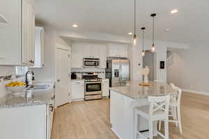 Kitchen with light wood-style flooring, a sink, white cabinetry, decorative backsplash, and stainless steel appliances