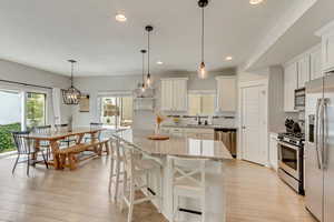 Kitchen featuring white cabinetry, light wood-type flooring, stainless steel appliances, and a sink