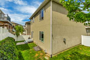 View of side of home featuring a yard, stucco siding, and fence